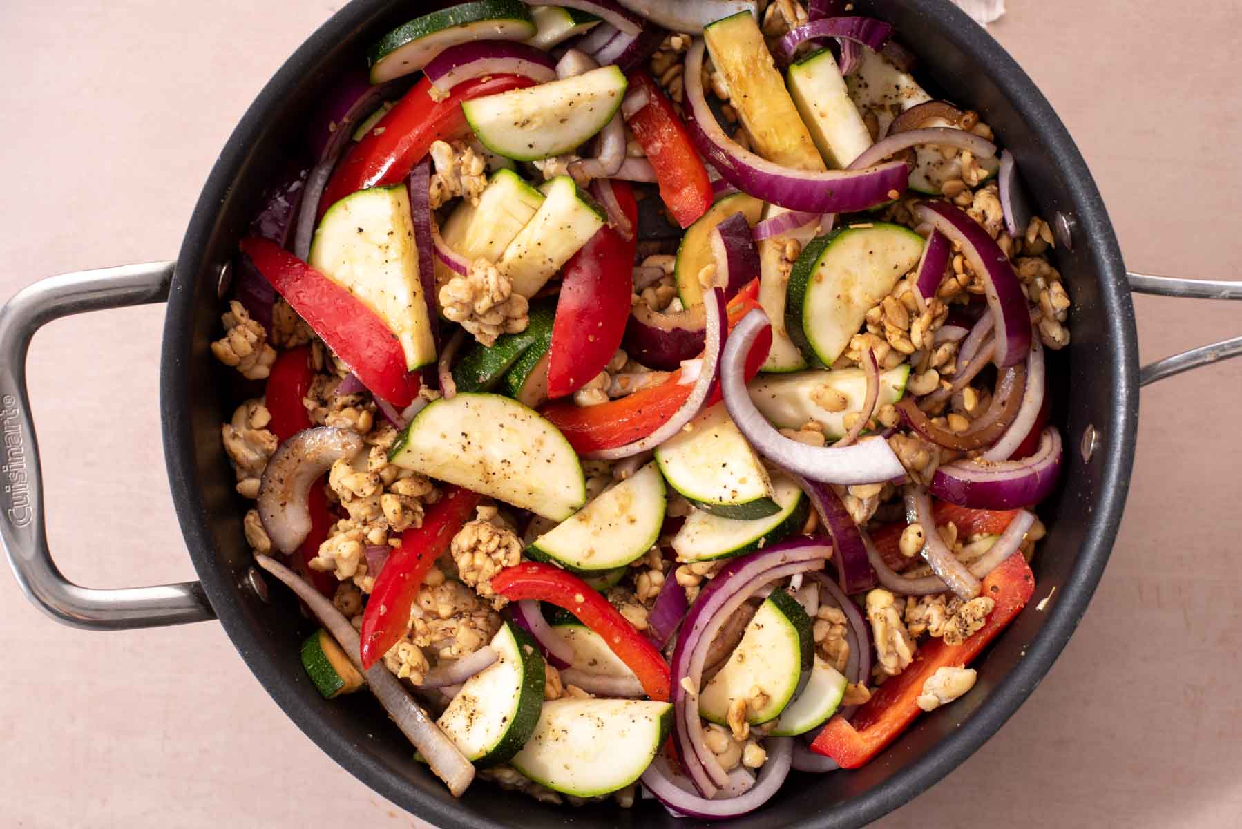 Vegetables and tempeh in a black pan before cooking.