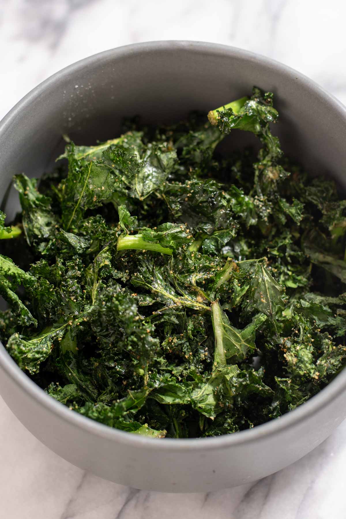 Close up of kale chips in a gray bowl.