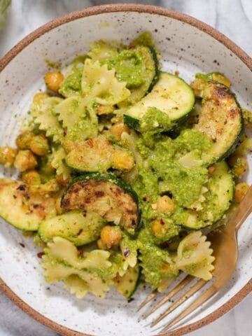 Overhead view of vegetarian pesto topped with extra pesto, zucchini, and chickpeas.