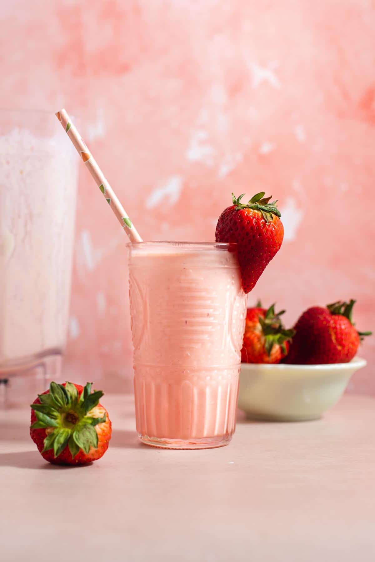 Pink glass filled with a pink strawberry peach smoothie.