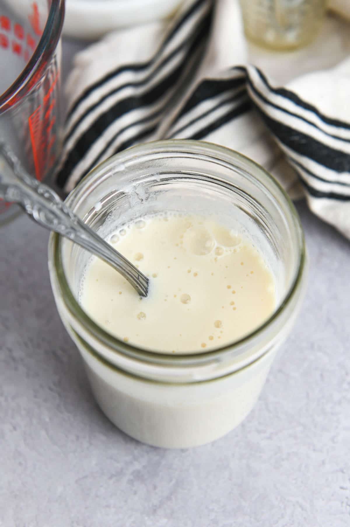 Spoon in a glass jar filled with buttermilk.