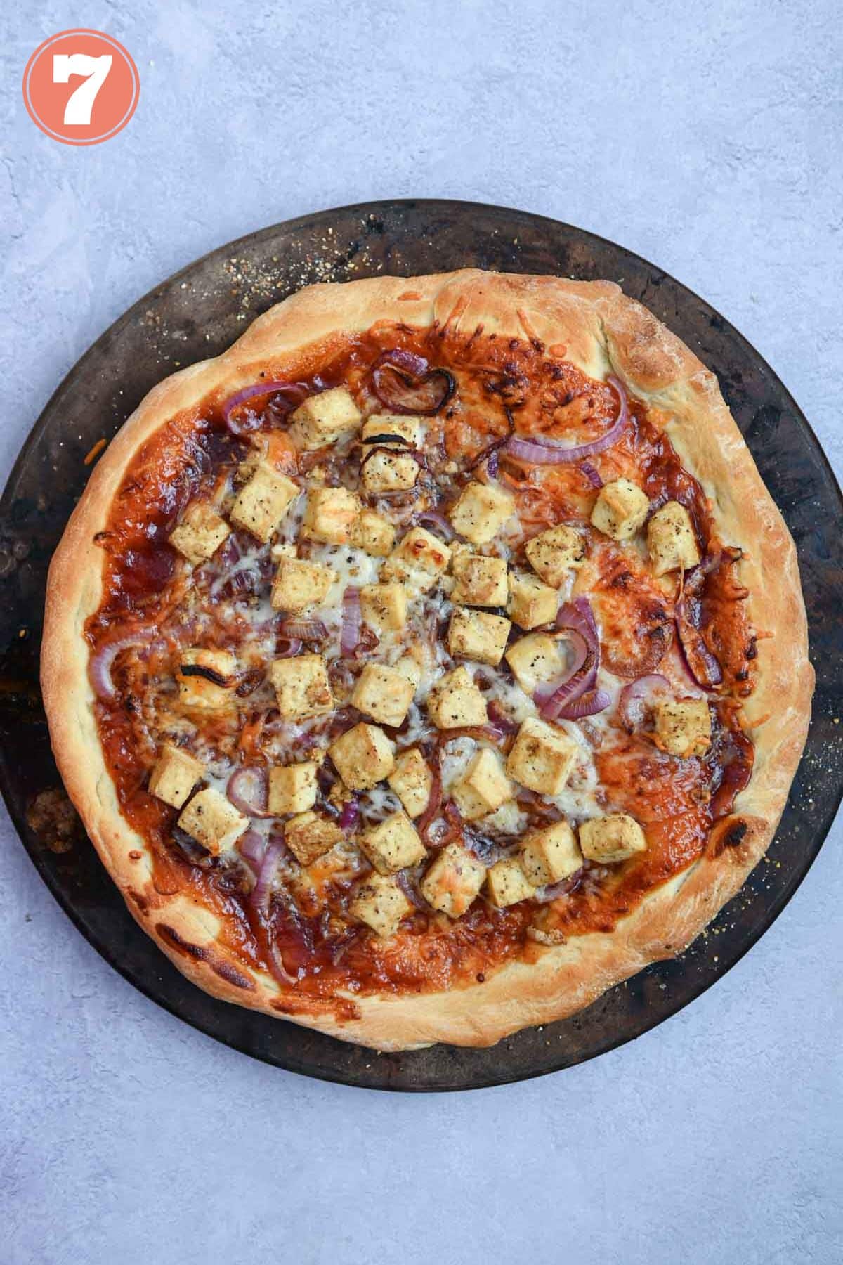 Cooked BBQ tofu pizza on a pizza stone.