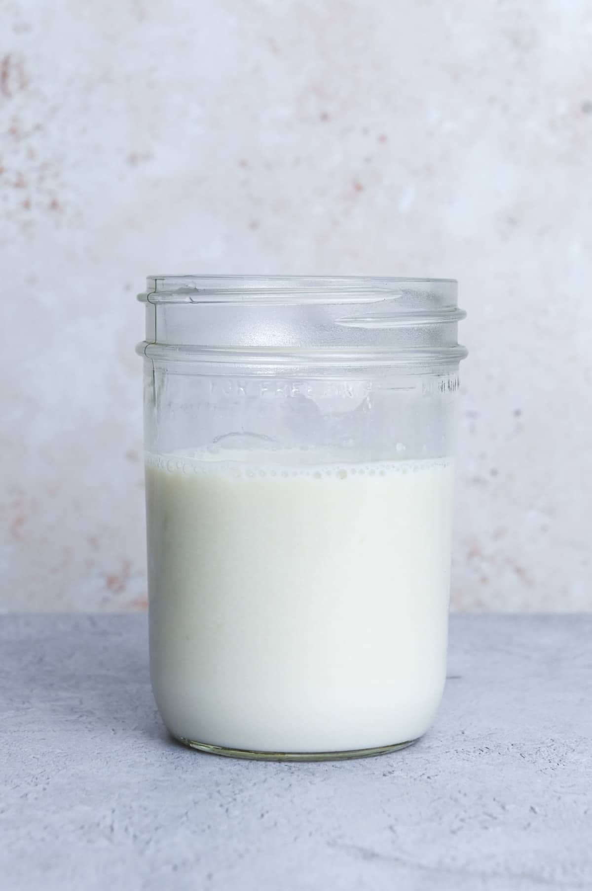 Glass of buttermilk in front of a gray background.