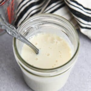 Spoon in a glass jar filled with buttermilk.