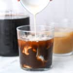 Milk being poured into a glass of cold brew.
