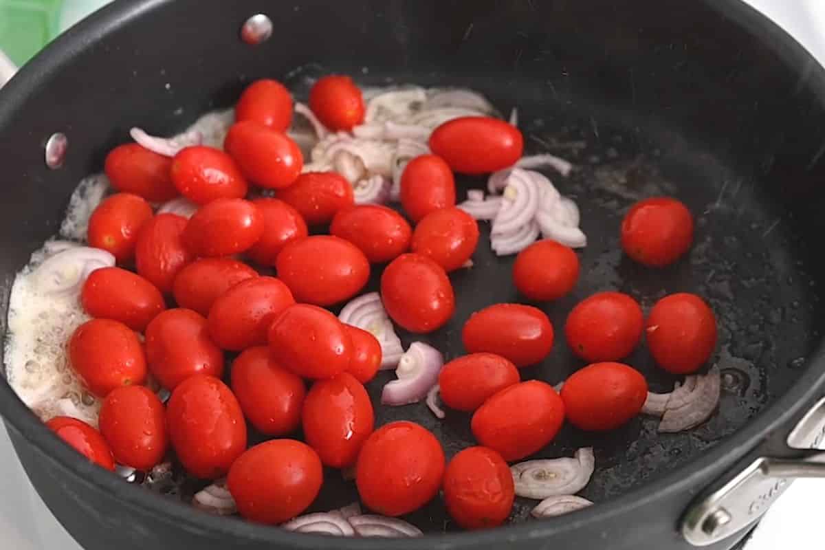 Cherry tomatoes and shallots in a pan.