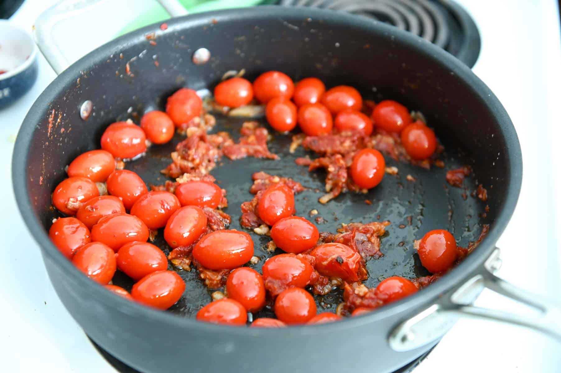 Cherry tomatoes cooking in a skillet.