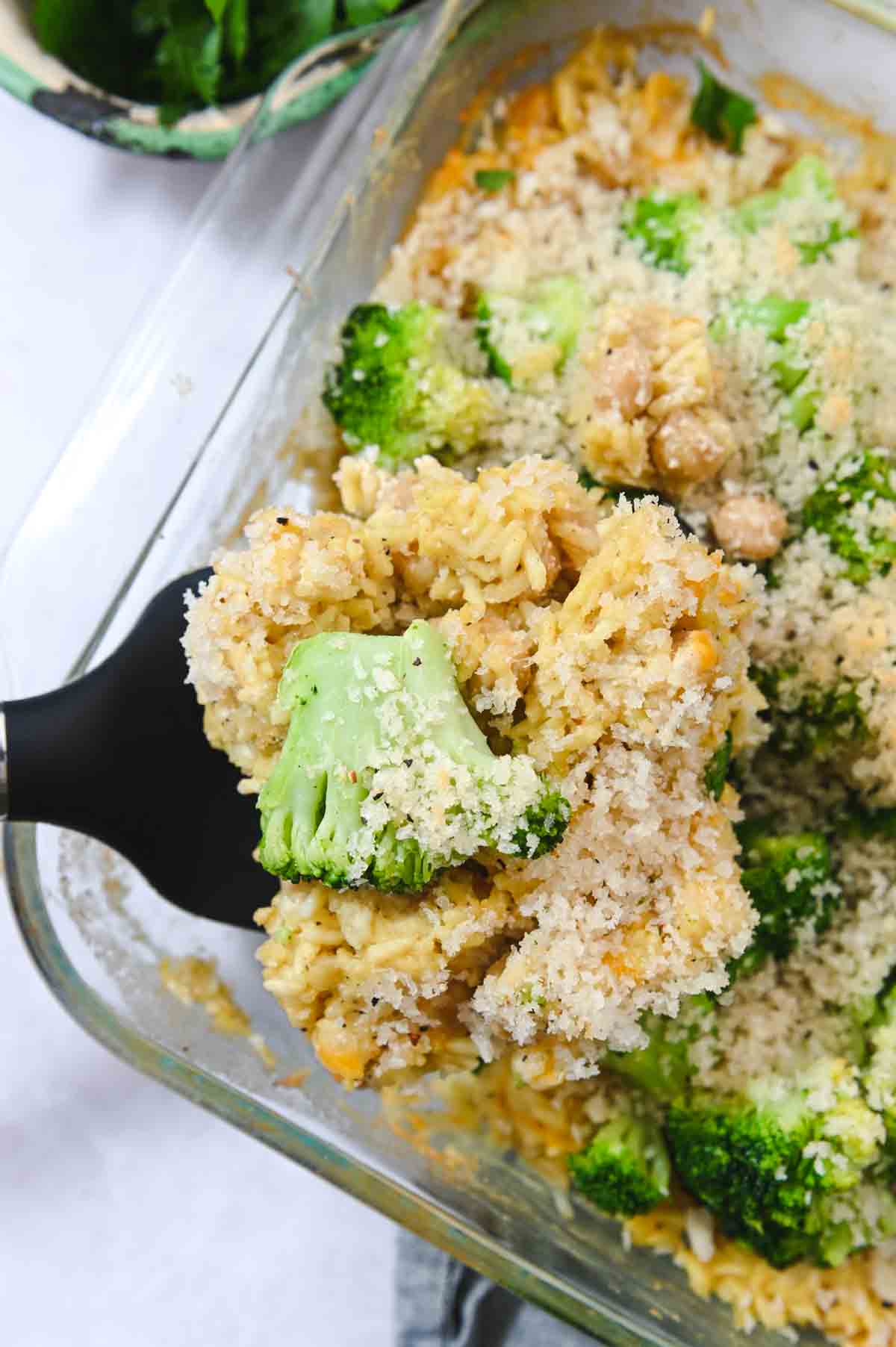 Spatula lifting a square of broccoli rice casserole out of a baking dish.