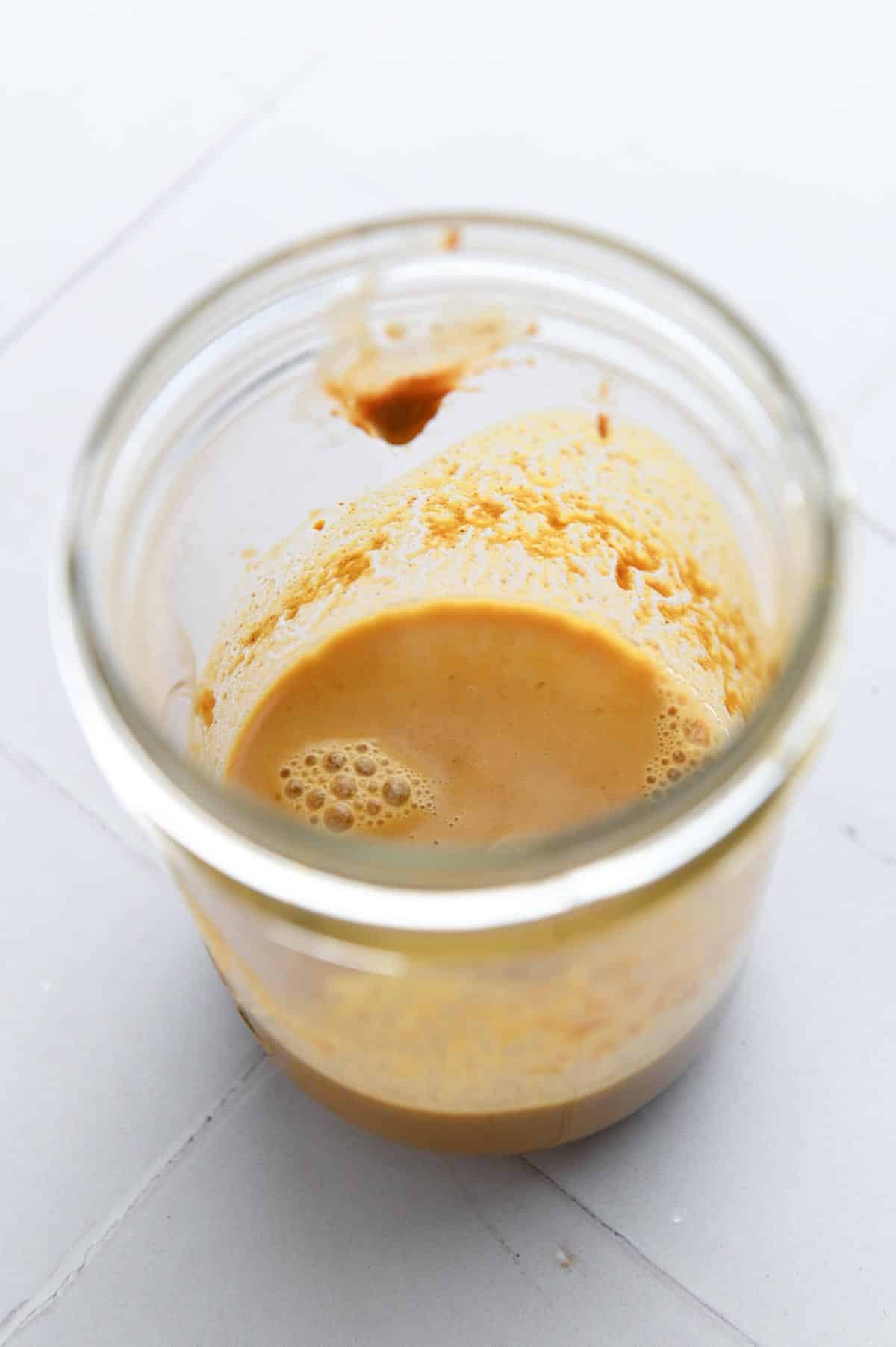 Gold-colored sauce in a glass jar.