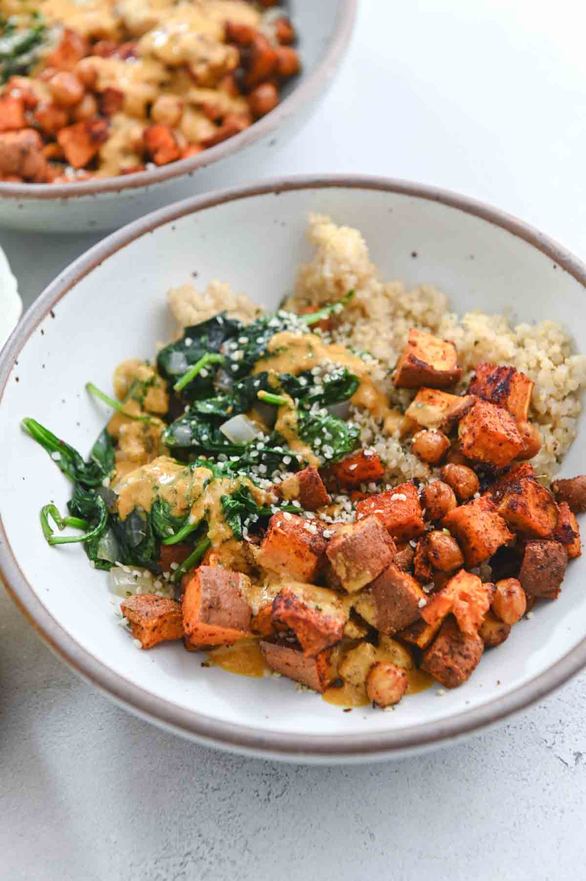 Close up of roasted sweet potato, spinach, and quinoa in a gray bowl.