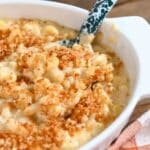 Close up of mac and cheese topped with toasted panko with a blue specked serving spoon.