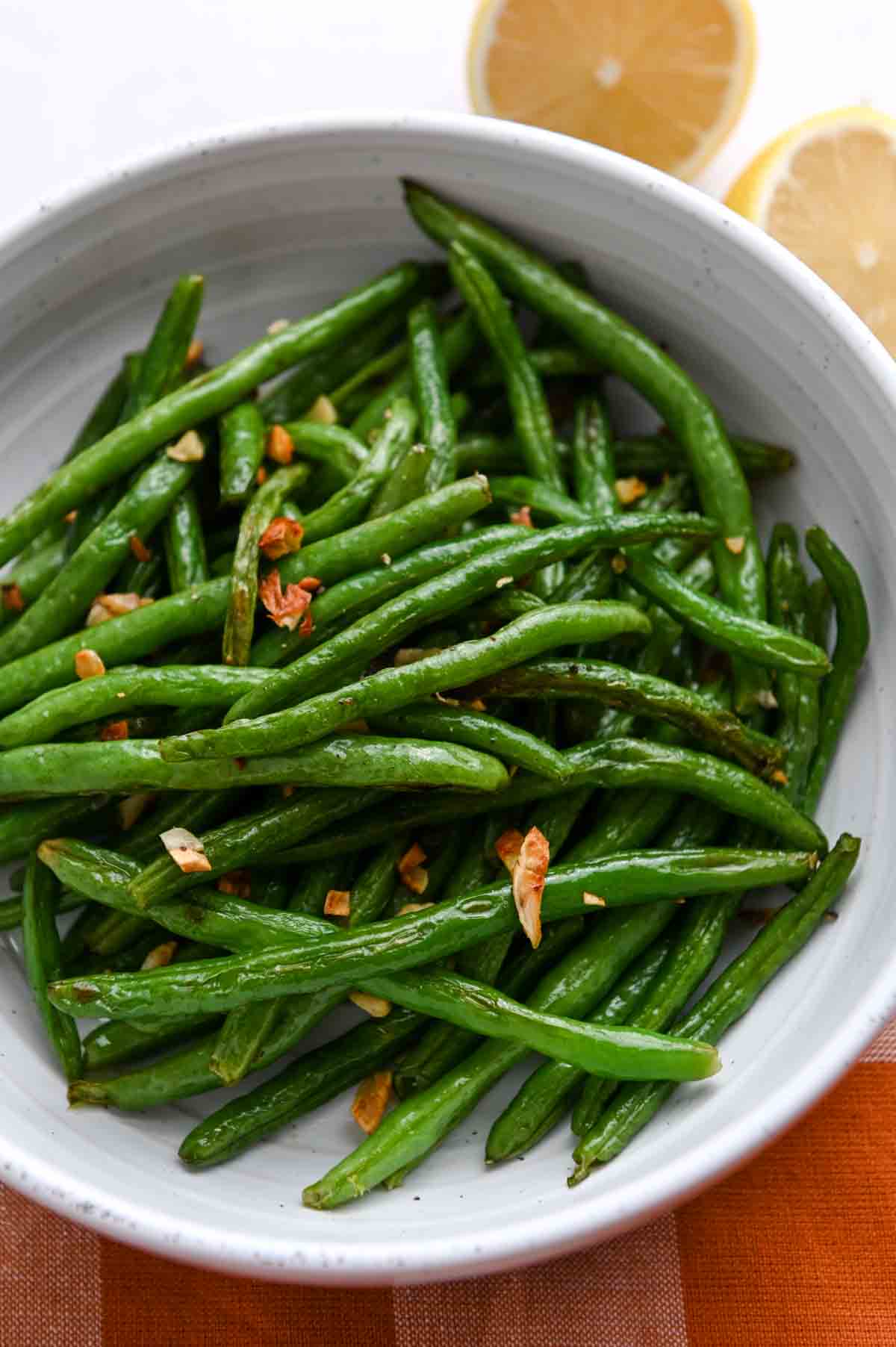 Roasted green beans in a bowl with golden garlic.