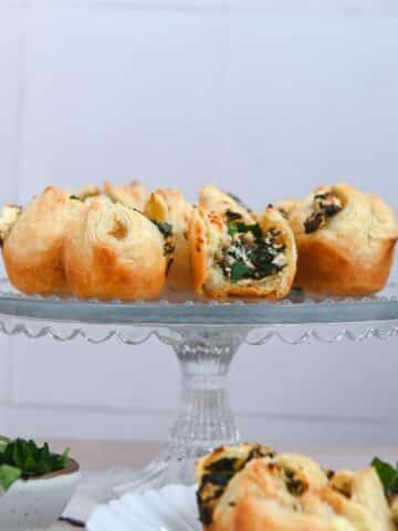 Glass cake stand topped with puff pastry bites.
