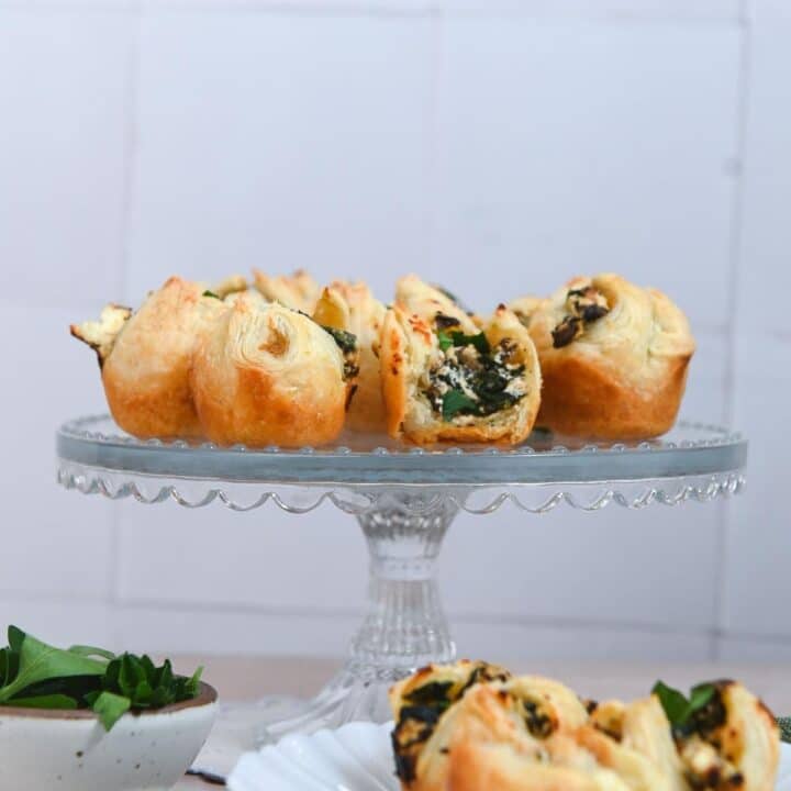 Glass cake stand topped with puff pastry bites.