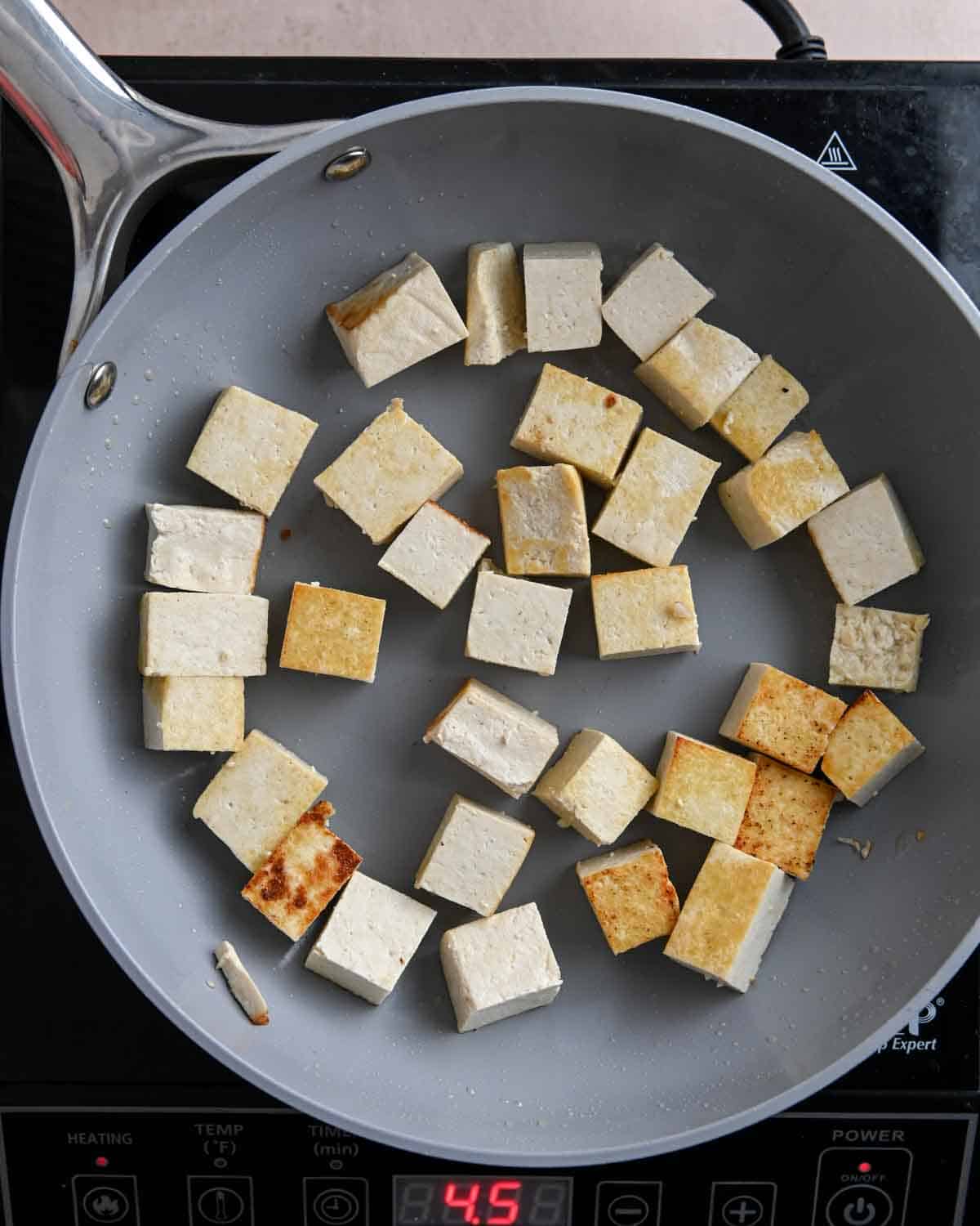 Cubed tofu with golden edges in a skillet.