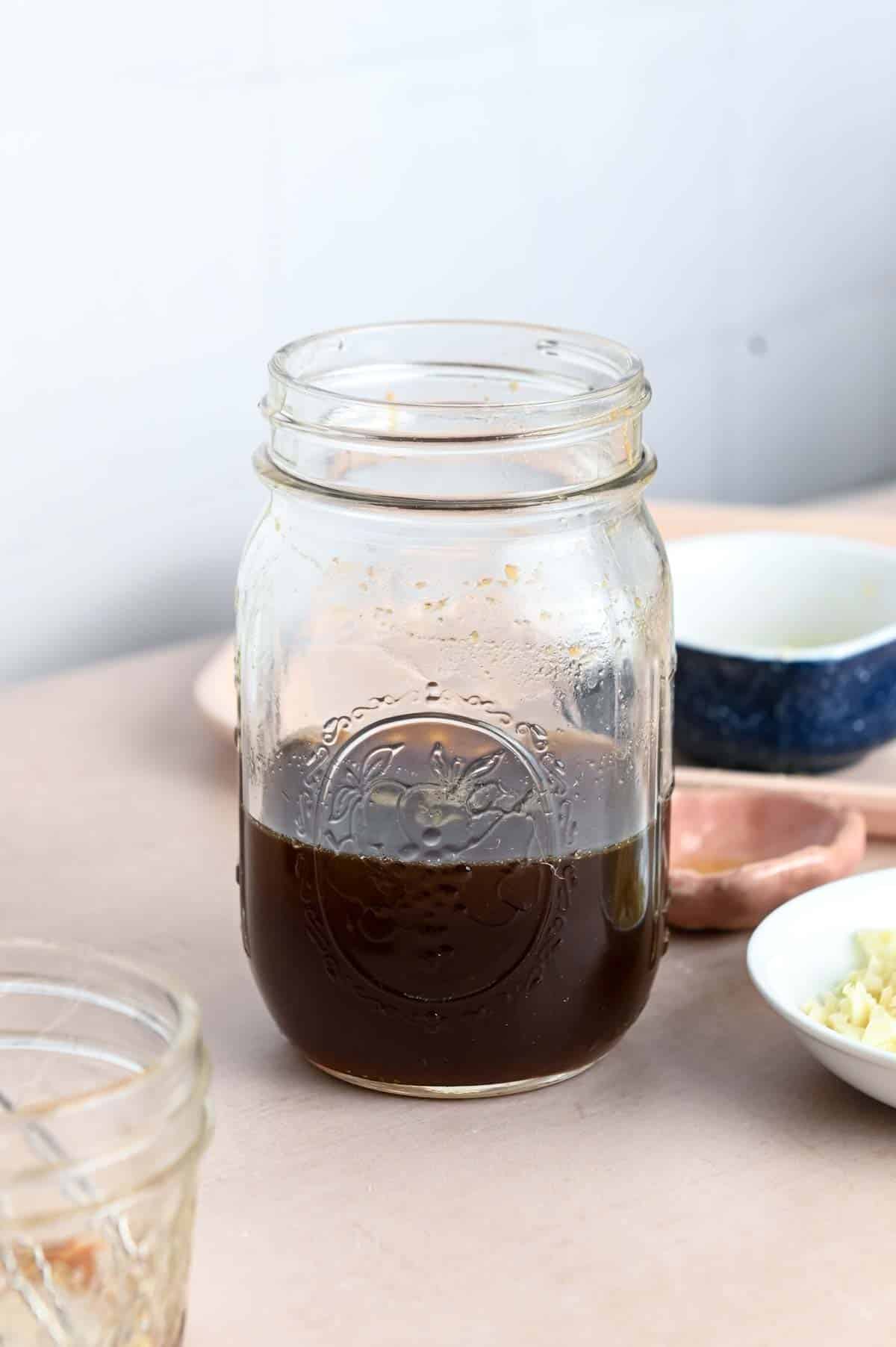 Brown honey garlic sauce in a pint-sized glass mason jar.