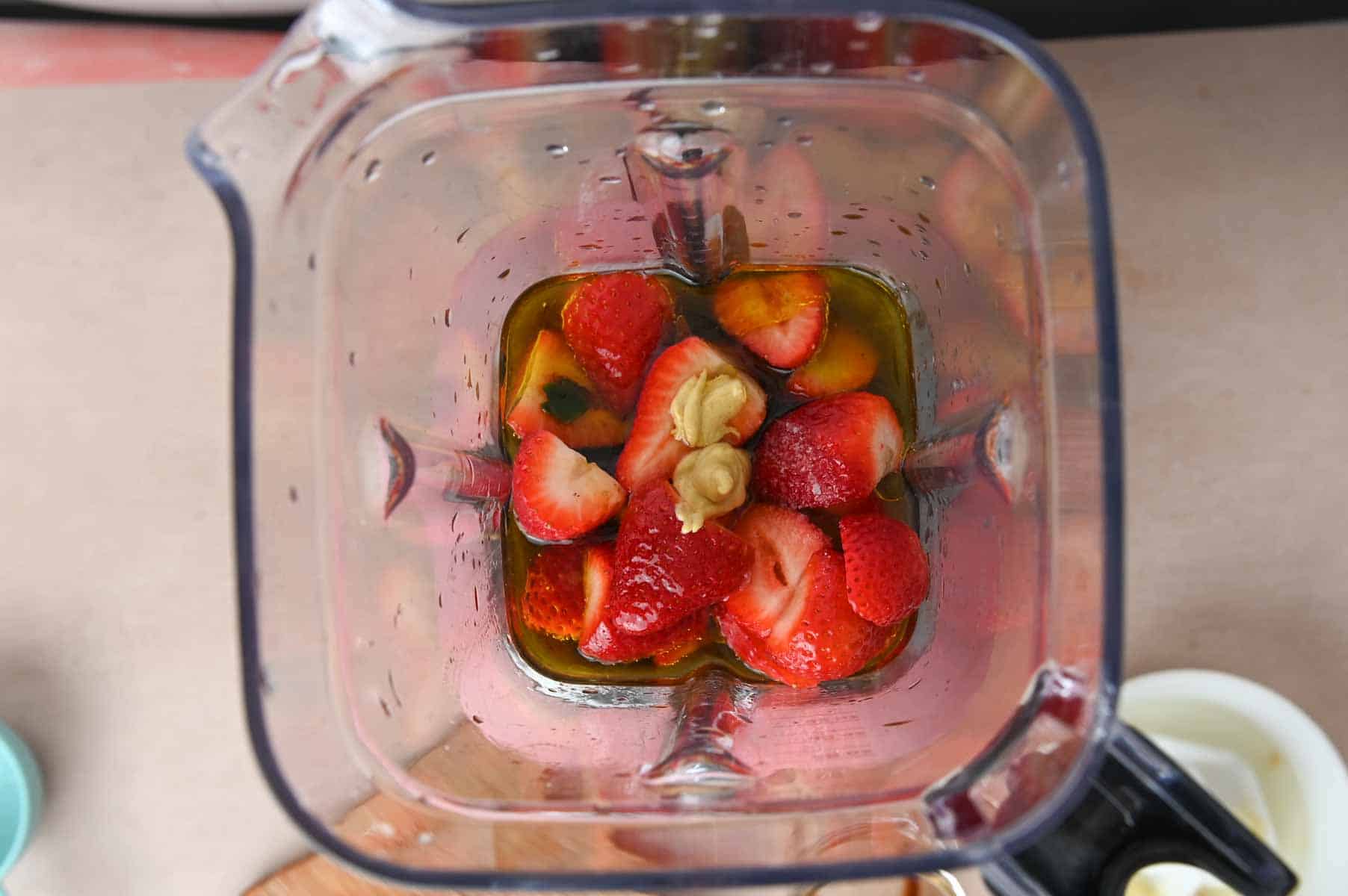 Top-down view of blender filled with unblended strawberries and vinegar.