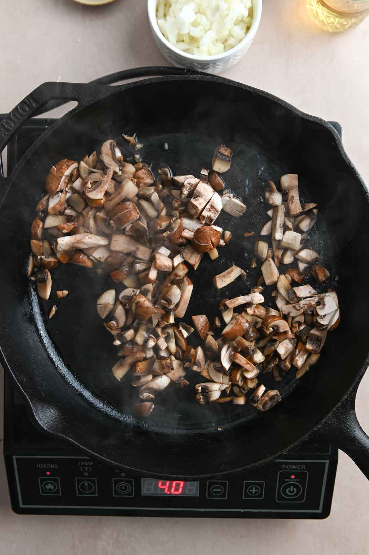 Chopped mushrooms sautéing in a cast iron pan.