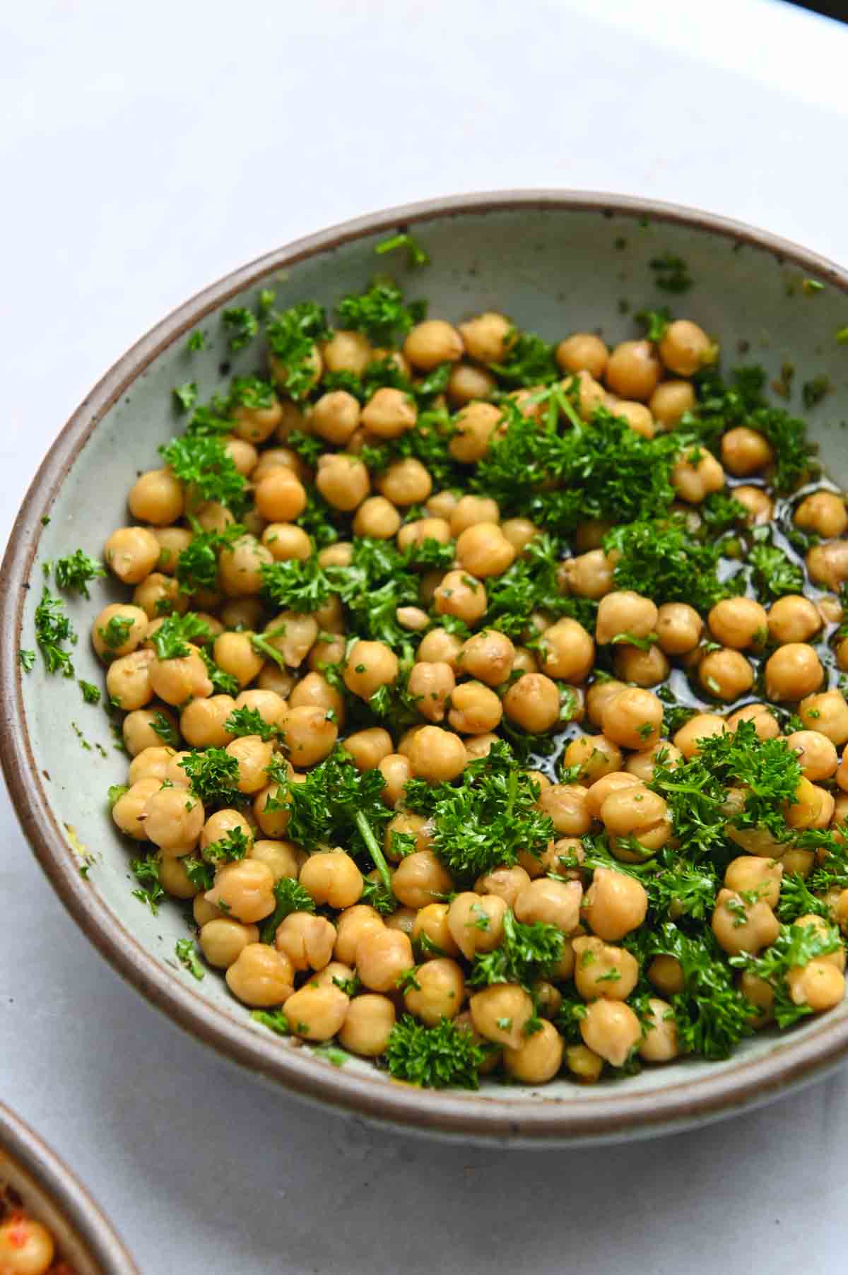 Close up of chickpeas and parsley in a gray bowl.