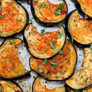 Close up of half moons of roasted eggplant topped with chopped cilantro.