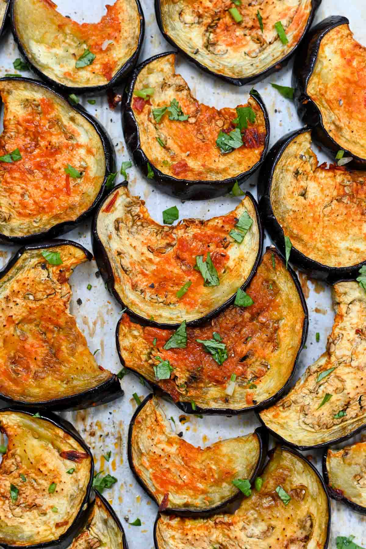 Close up of half moons of roasted eggplant topped with chopped cilantro.
