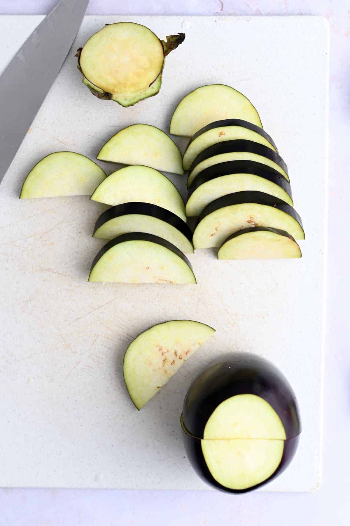 Slices of eggplant on a white cutting board.
