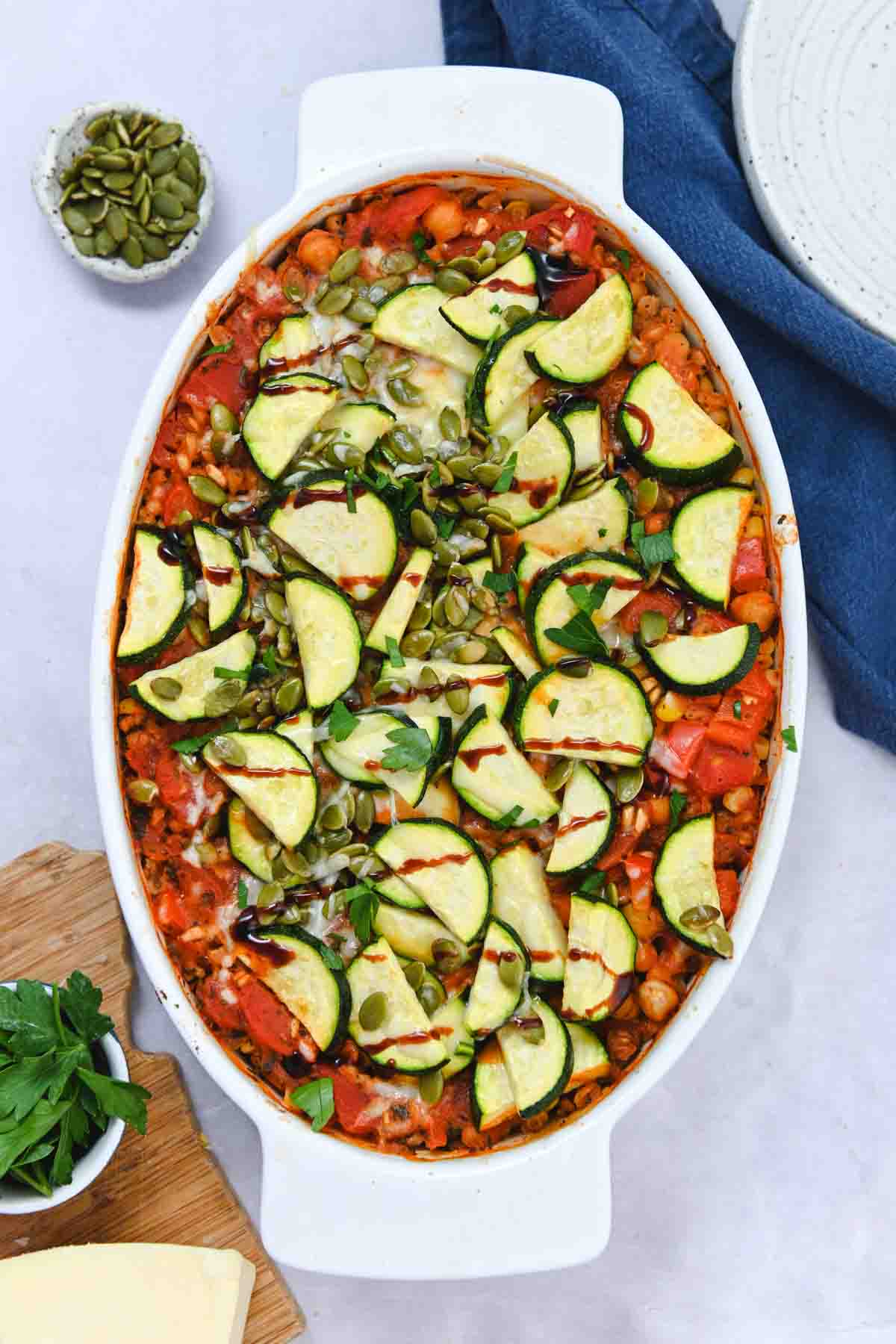 White oval baking dish with zucchini on top.