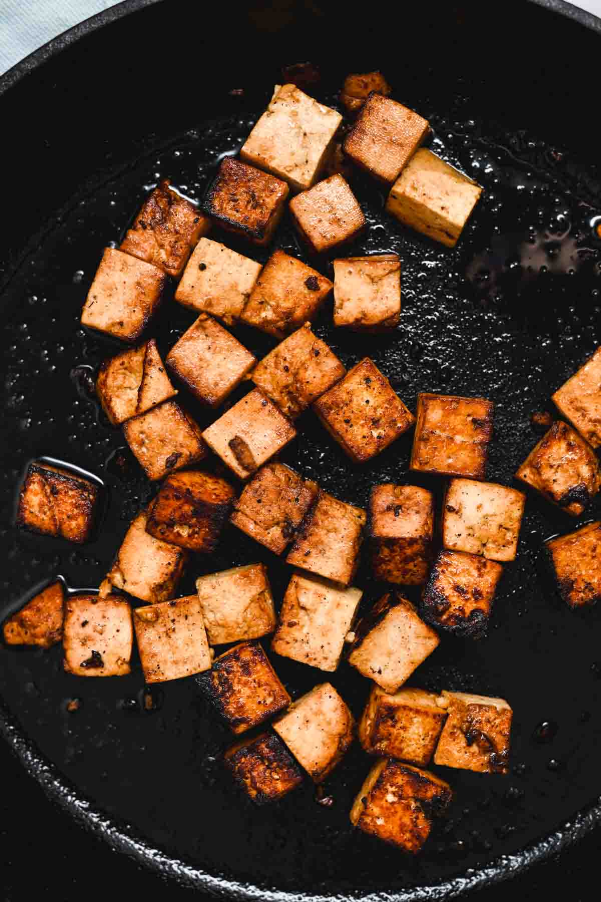 Golden tofu in a cast iron skillet.
