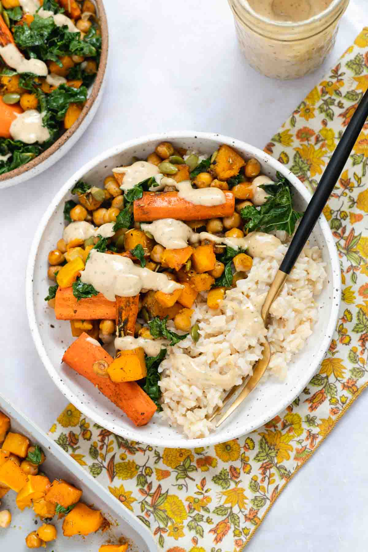 White bowl filled with roasted butternut squash, brown rice, and a drizzle of tahini dressing.