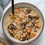 Mushroom wild rice soup in a gray bowl with a gold and black spoon.