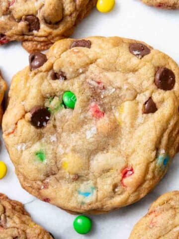 M&M chocolate chip cookie surrounded by mini M&Ms and more cookies.