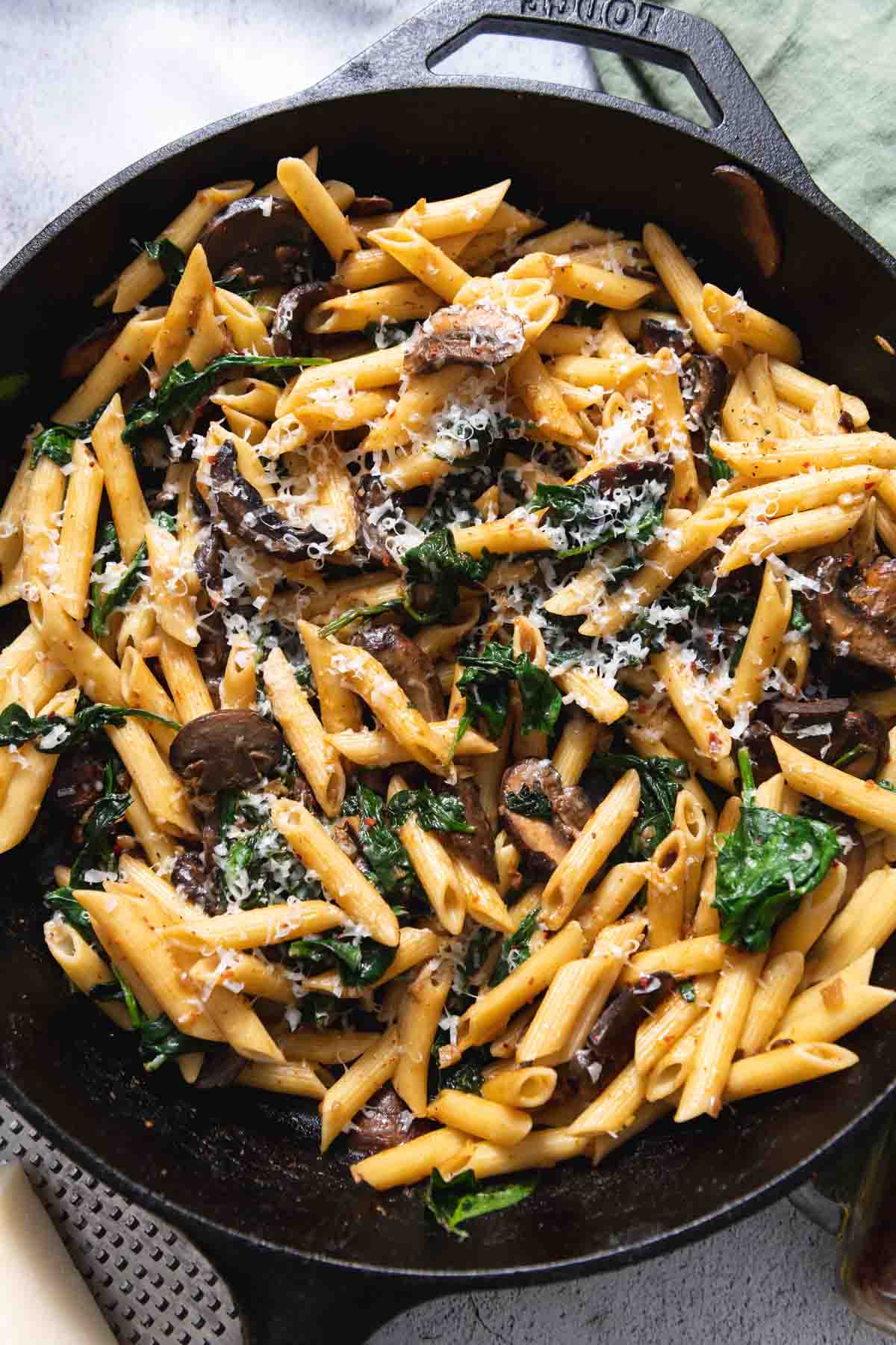 Close up of mushroom spinach penne pasta in a cast iron skillet.