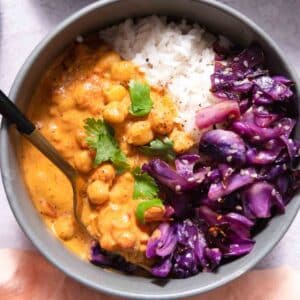 Gray bowl filled with curry chickpeas, red cabbage, and rice.
