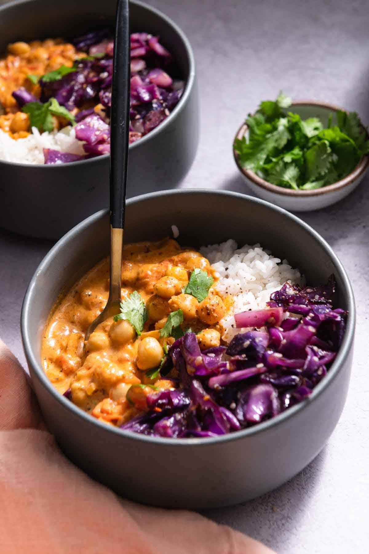 Side view of bowl of chickpea curry with rice and red cabbage.