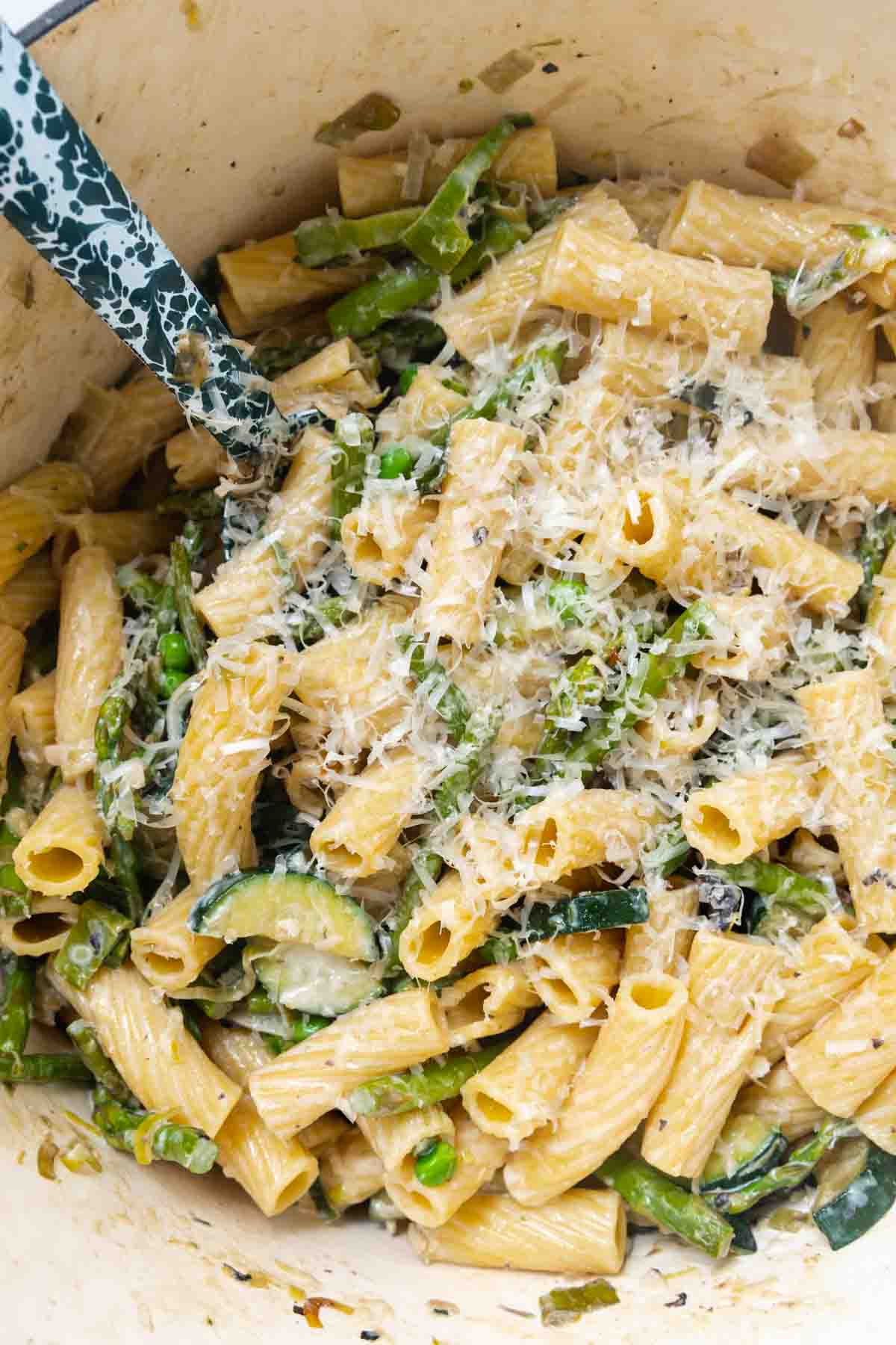 Close up of rigatoni and vegetables topped with Parmesan.