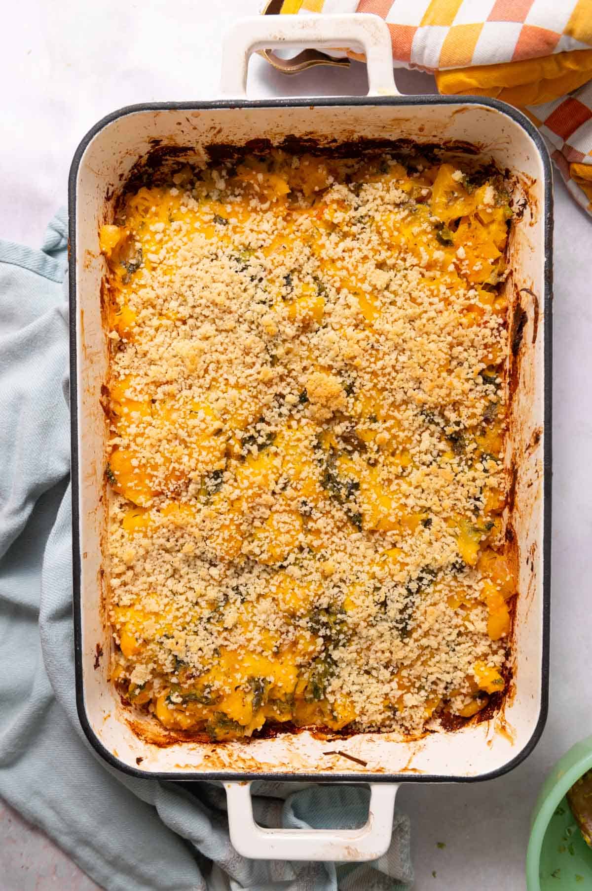 Overhead view of white handled enamel baking dish filled with panko-topped butternut squash casserole.