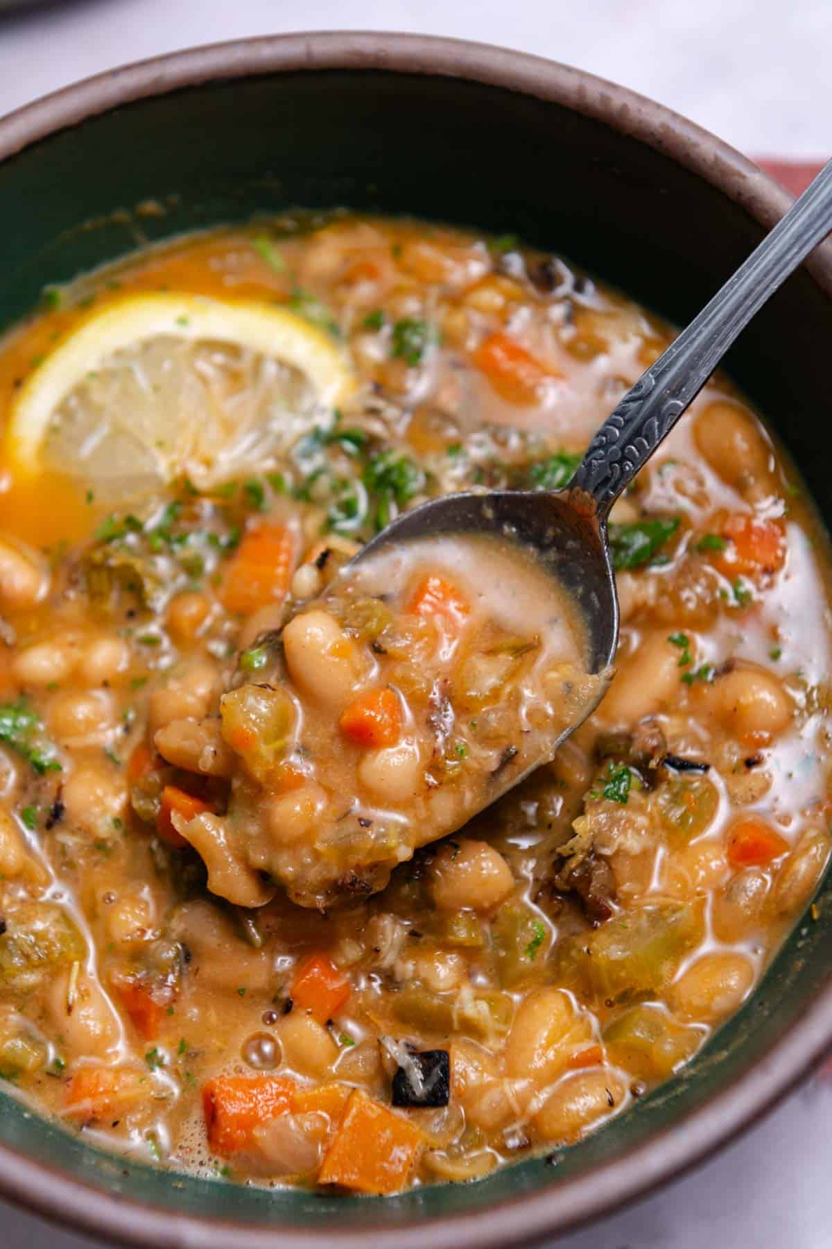 Close up of decorative silver spoon lifting a bite of white beans out of the white bean soup.