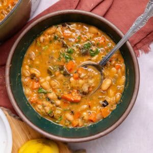 Green bowl with white bean soup and a spoon in it.