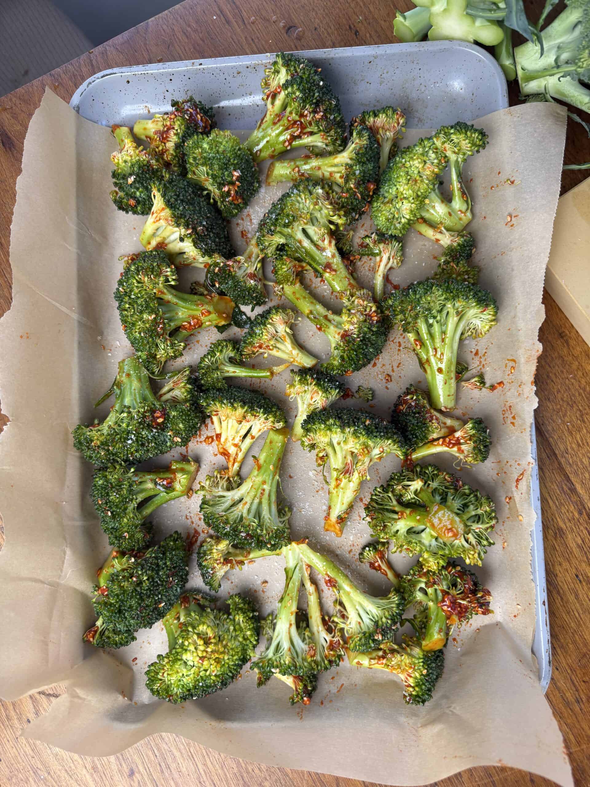 Broccoli florets on a parchment paper lined baking sheet.
