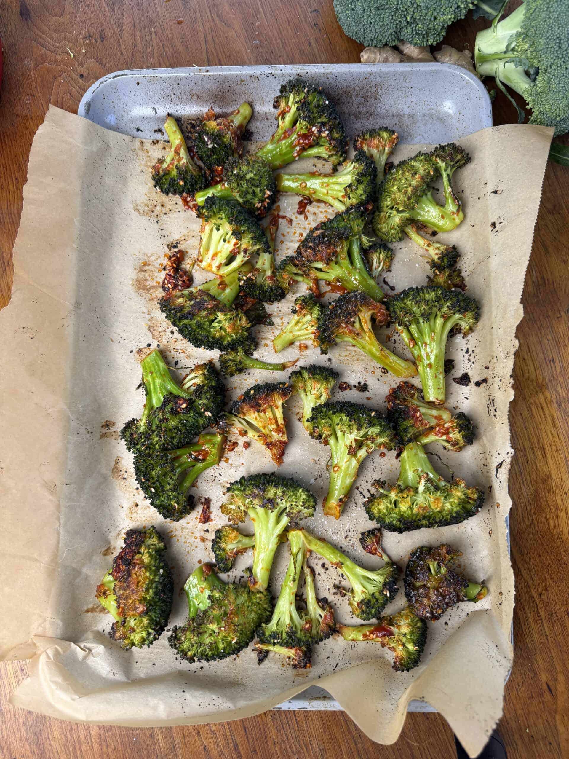 Broccoli florets on the parchment paper lined sheet pan after roasting.
