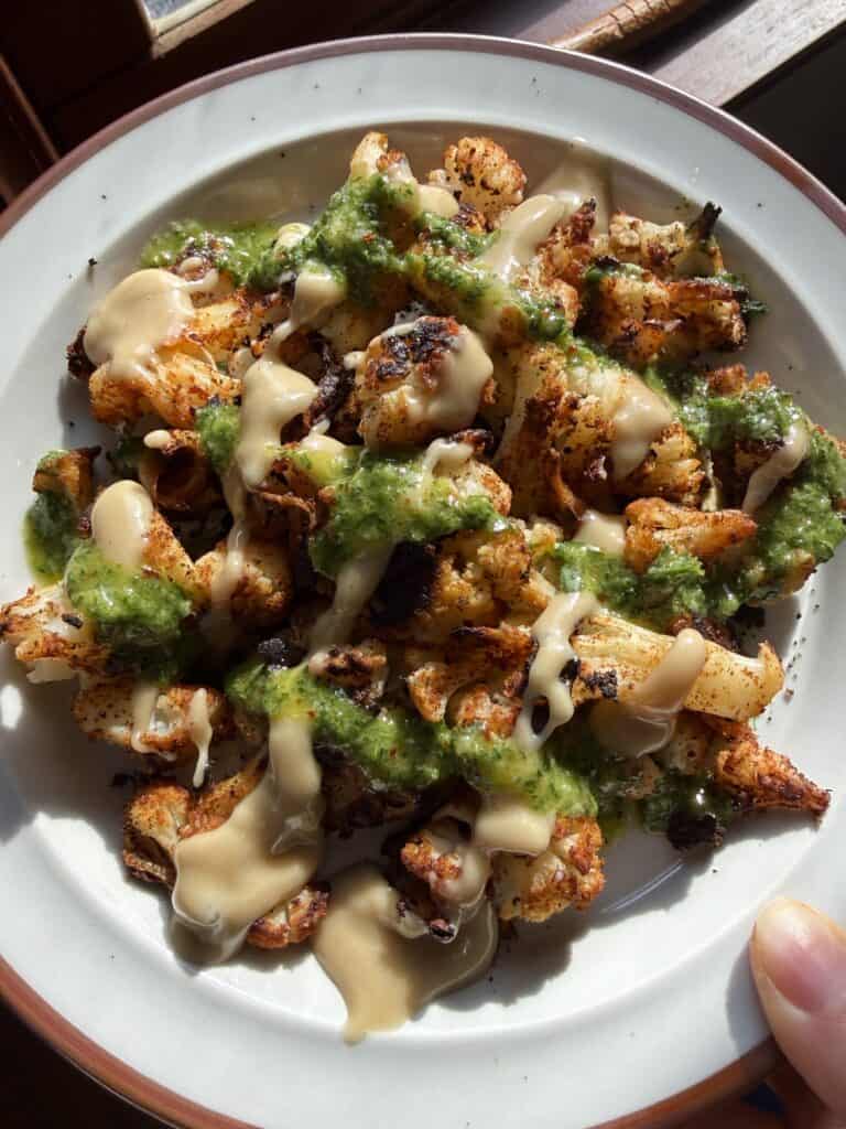 Close up of blackened roasted cauliflower with sauces in a grid formation.