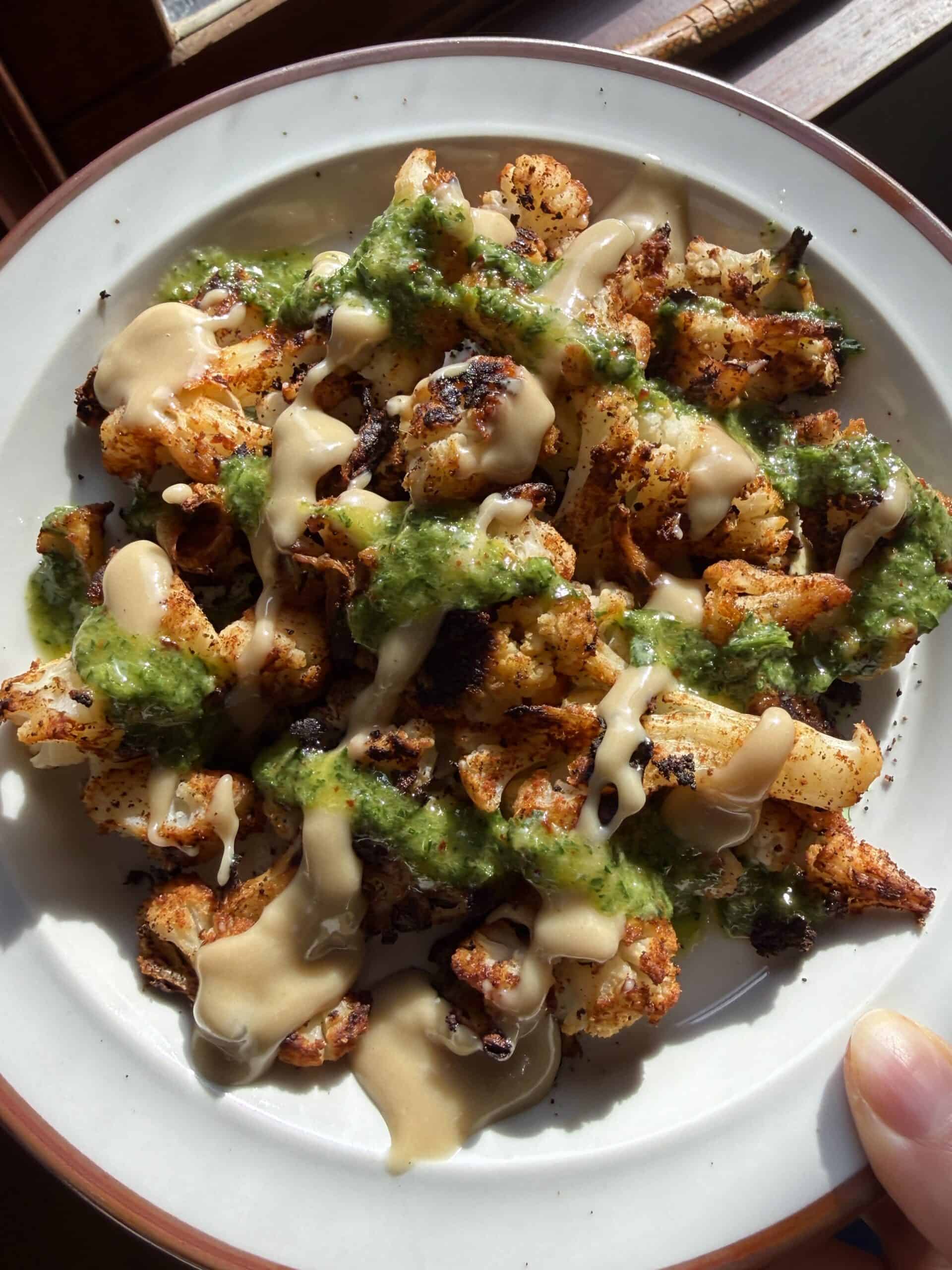 Close up of blackened roasted cauliflower with sauces in a grid formation.