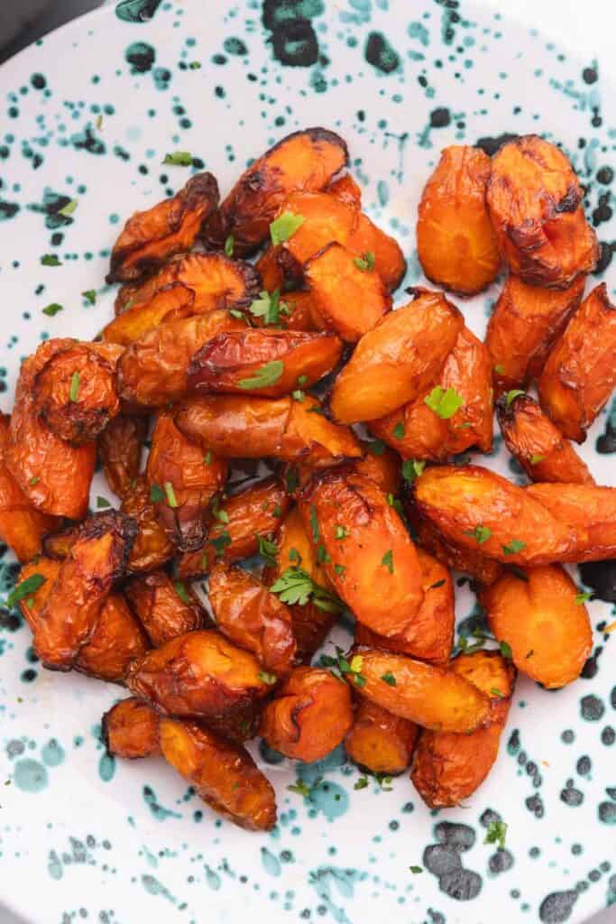 Close up of roasted carrot coins in a blue speckled bowl.