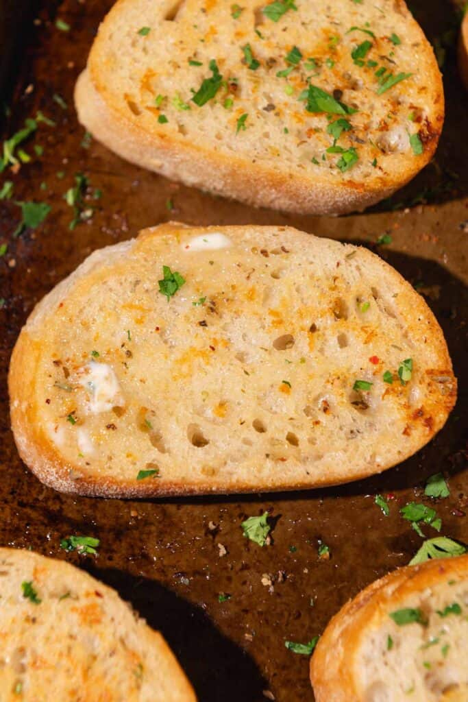 Close up of garlic toast topped with chopped parsley.
