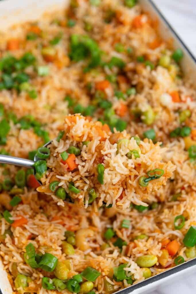 Scoop of rice being lifted out of casserole dish.