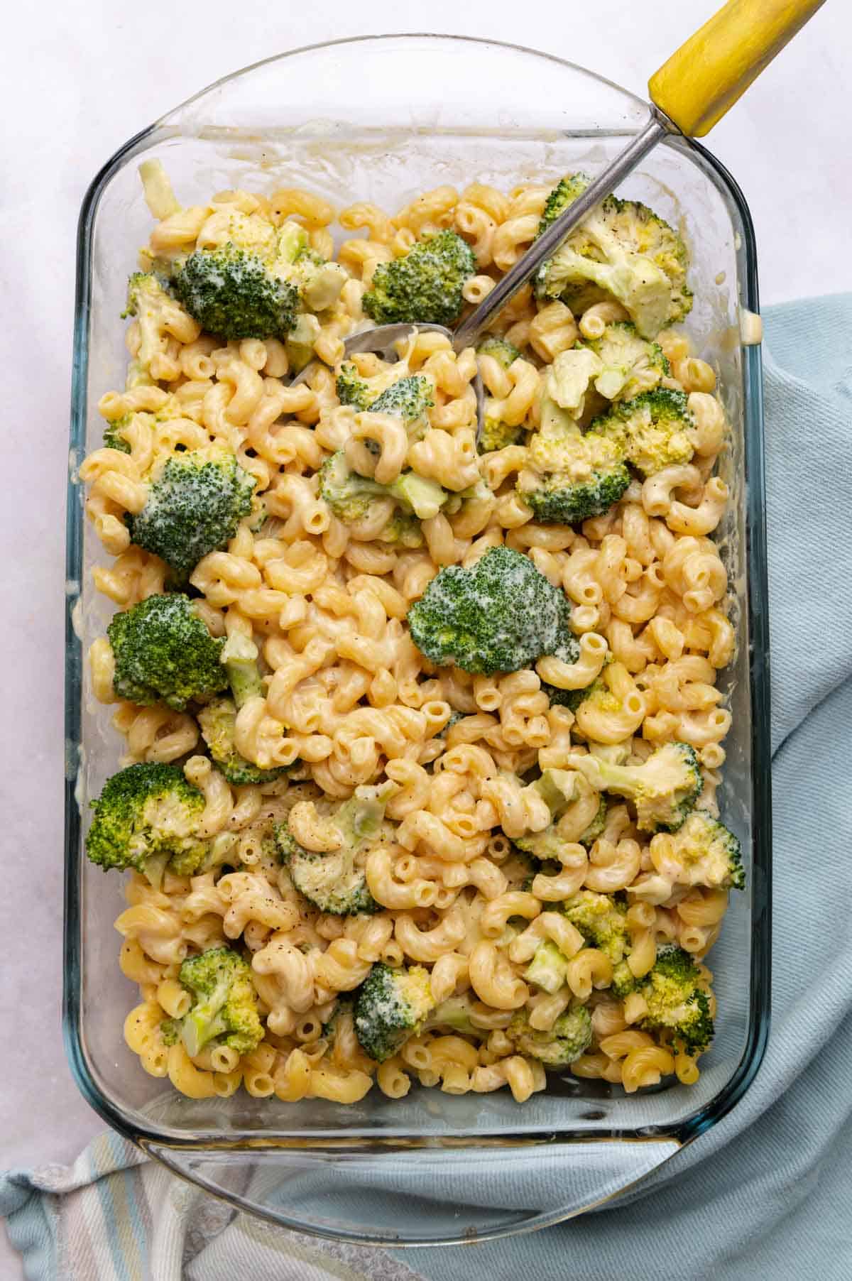 Overhead view of pasta in a glass baking dish on a blue cloth.