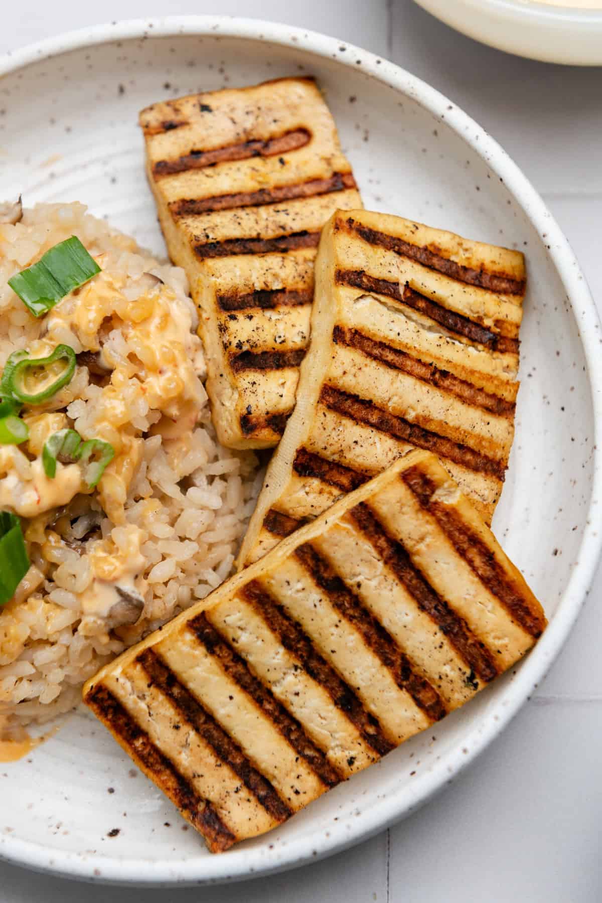 Three pieces of grilled tofu slabs with char marks on them.