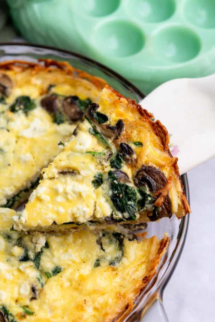 Slice of hashbrown quiche being removed from a pie plate.