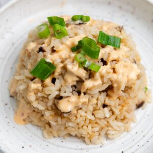 White plate with large scoop of miso mushroom rice with sliced green onions on top.