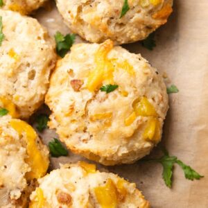 Close up top-down view of golden cheesy biscuit on parchment paper.